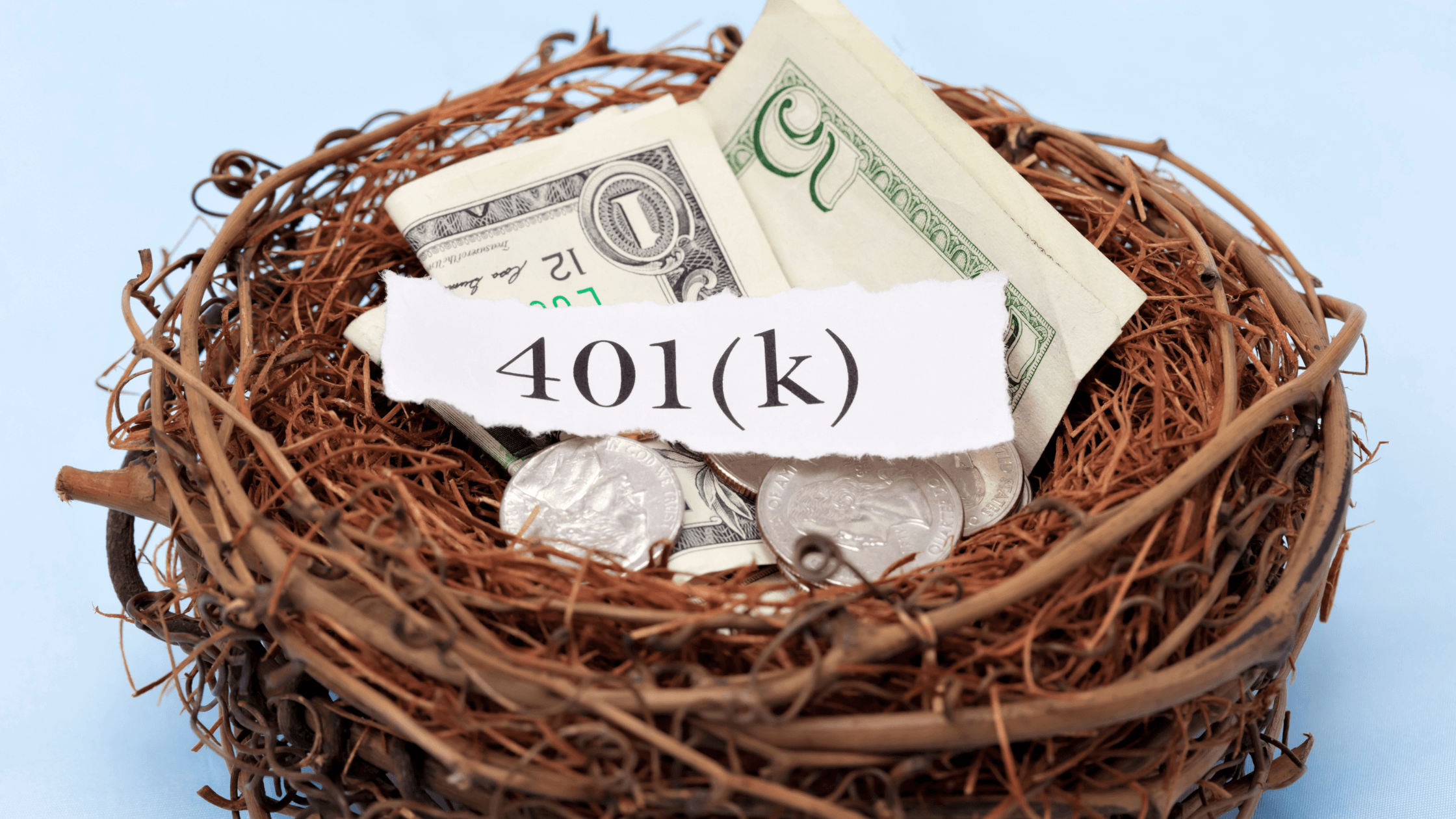A bird’s nest containing US dollar bills and coins with a torn piece of paper labeled "401(k)" resting on top, symbolizing retirement savings.