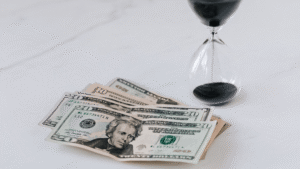 A fan of US twenty and ten-dollar bills next to an hourglass with black sand, symbolizing the limited time window for strategic tax planning.